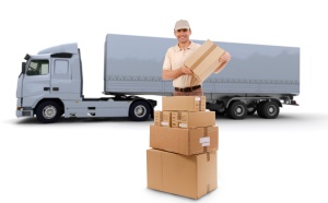 Isolated image of a messenger delivering a lot of boxes with a trailer truck in the background
